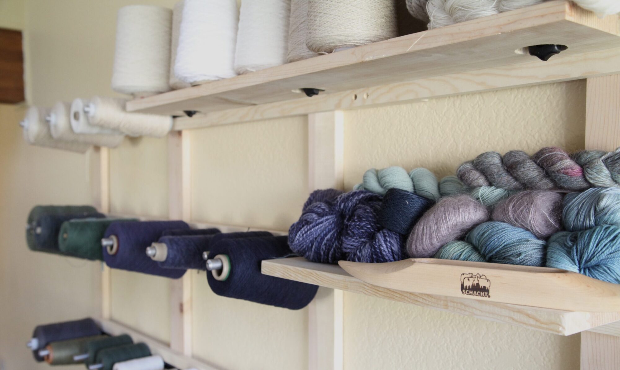 cones and skeins of yarn on a yarn rack.
